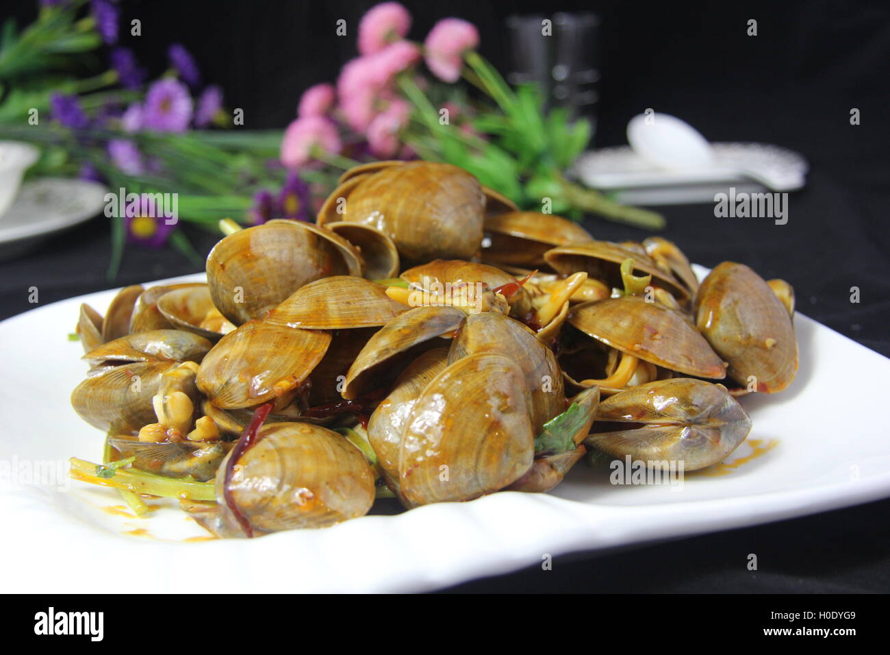 Pikante Muscheln mit Gemüse auf weißen Teller in schwarzem Hintergrund Stockfoto