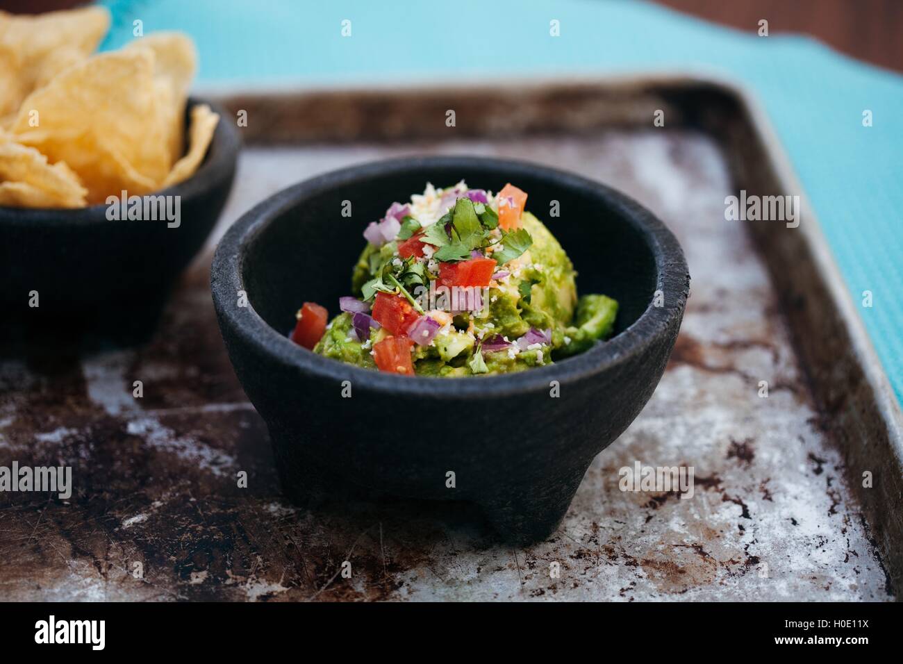 Gemischter Salat der zerdrückte Advocado, Tomaten, Zwiebeln und Kräutern auf schwarze Schale Stockfoto