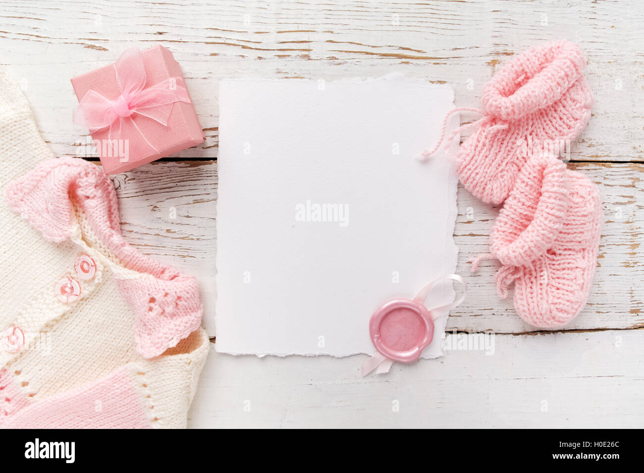 Baby Mädchen Kleidung, leere Karte mit Wachs versiegeln und kleines Geschenk-Box auf weißem Hintergrund aus Holz. Flach zu legen. Owerhad Ansicht Stockfoto