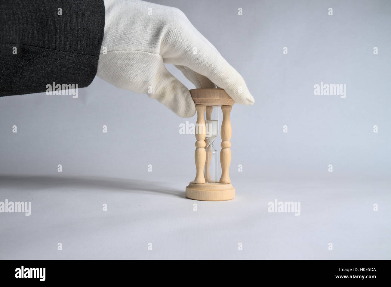 Weißen Handschuhen berühren eine Sanduhr. Geschäfts- und Unterkunft Industrie-Thema Stockfoto