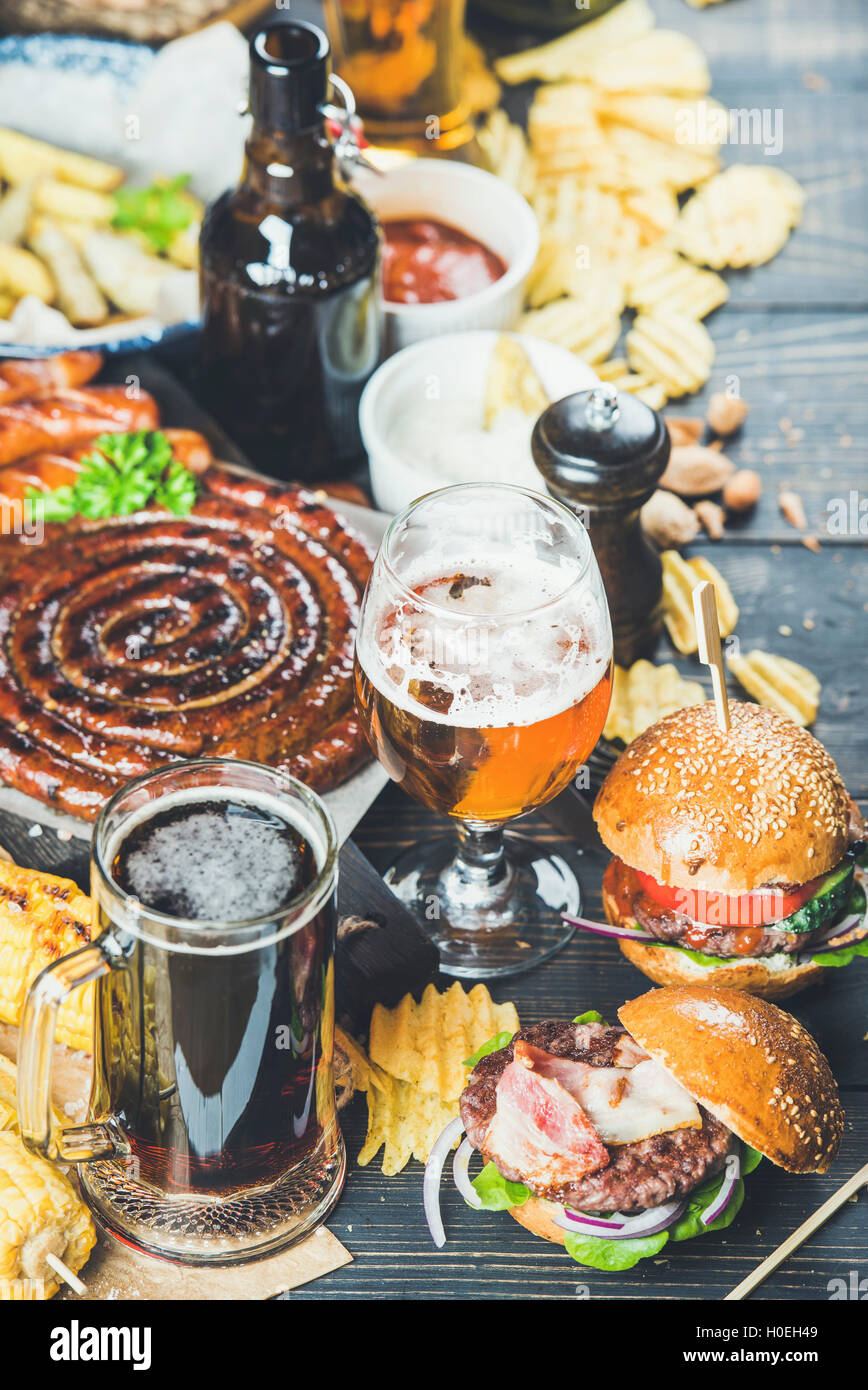 Bier und Brotzeit festgelegt. Oktoberfest-Essen-Frame-Konzept. Vielzahl von Bieren, gegrillte Würstchen, Burger, Pommes frites, Mais, Chips und s Stockfoto