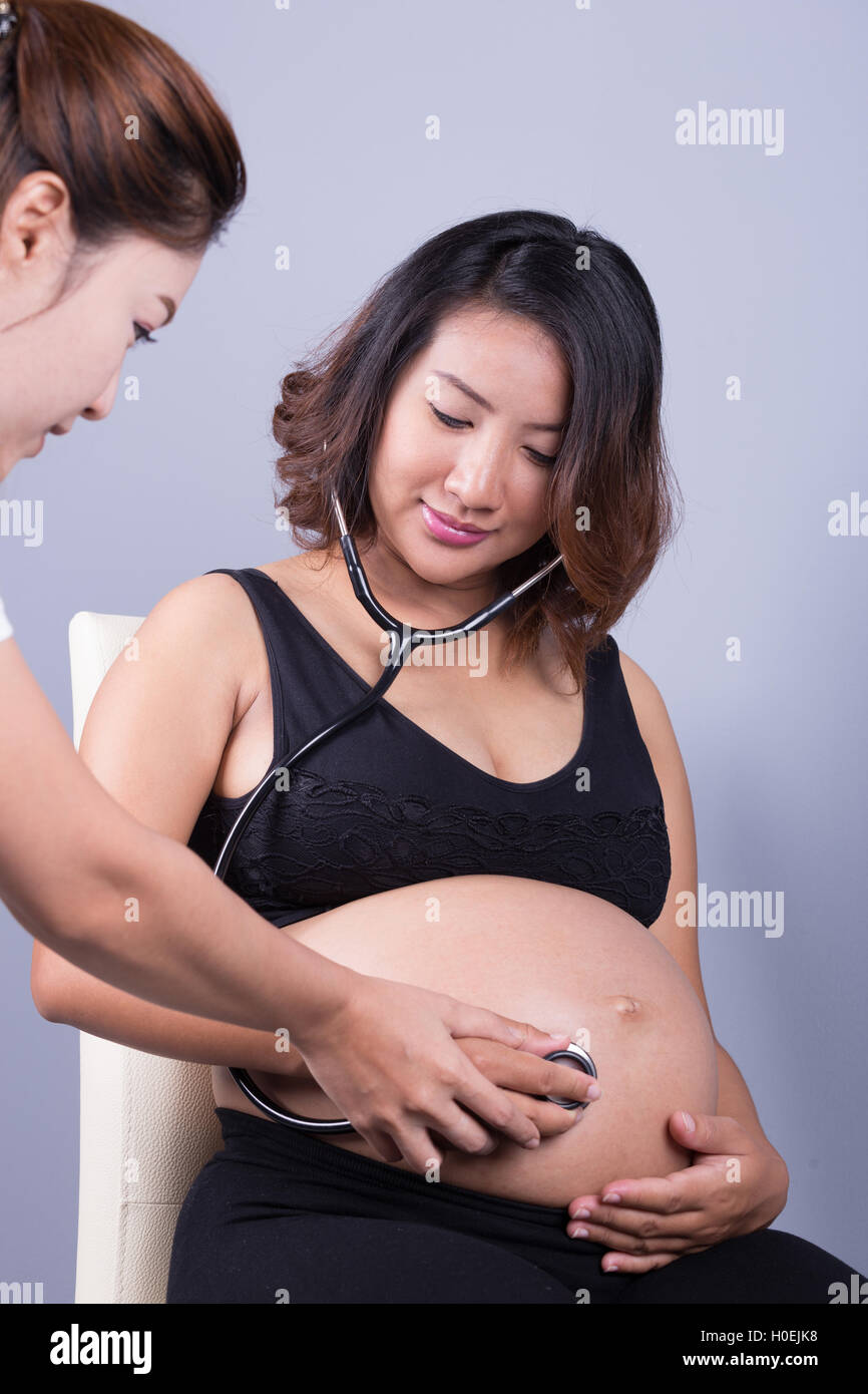 Bauch einer schwangeren Frau, die mit einem Stethoskop untersucht Stockfoto