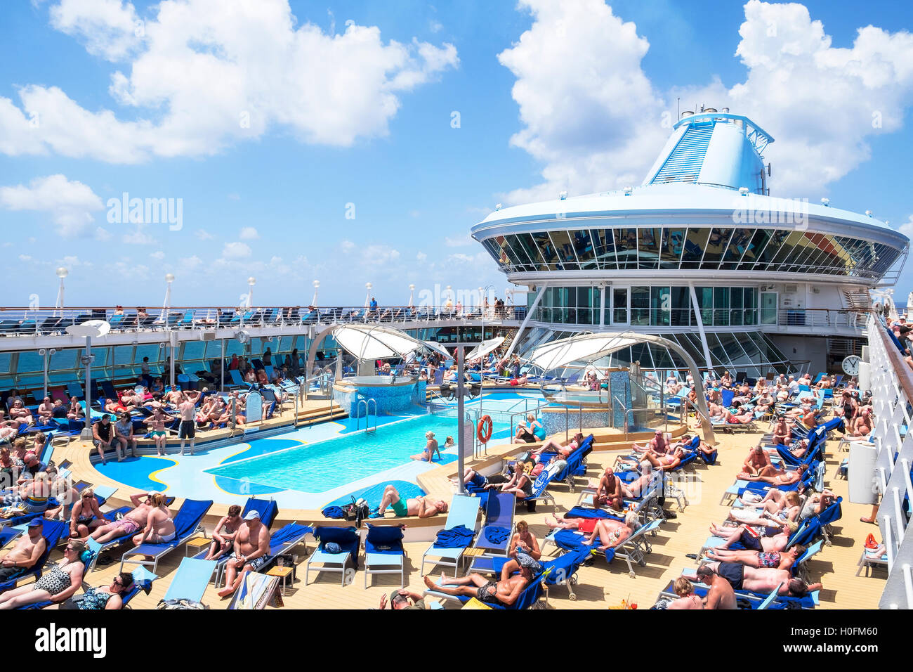 Passagiere genießen Sie die mediterrane Sonne auf dem Pooldeck ein Thomson Kreuzfahrtschiff. Stockfoto