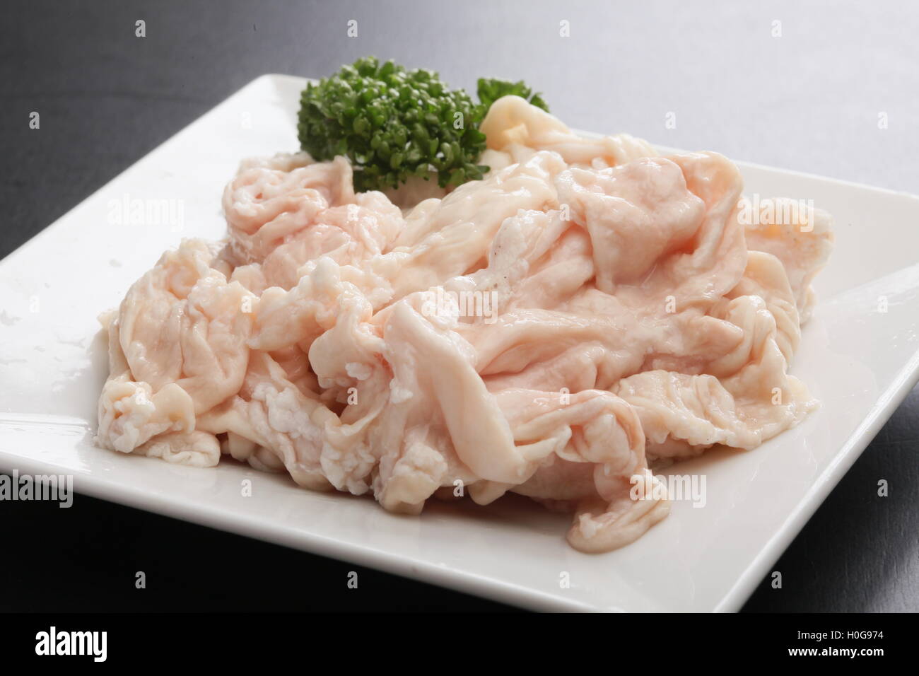 Frisches rohes Schwein Hormon Magen mit Kreuzkümmel Kräuter auf weißem Teller Stockfoto