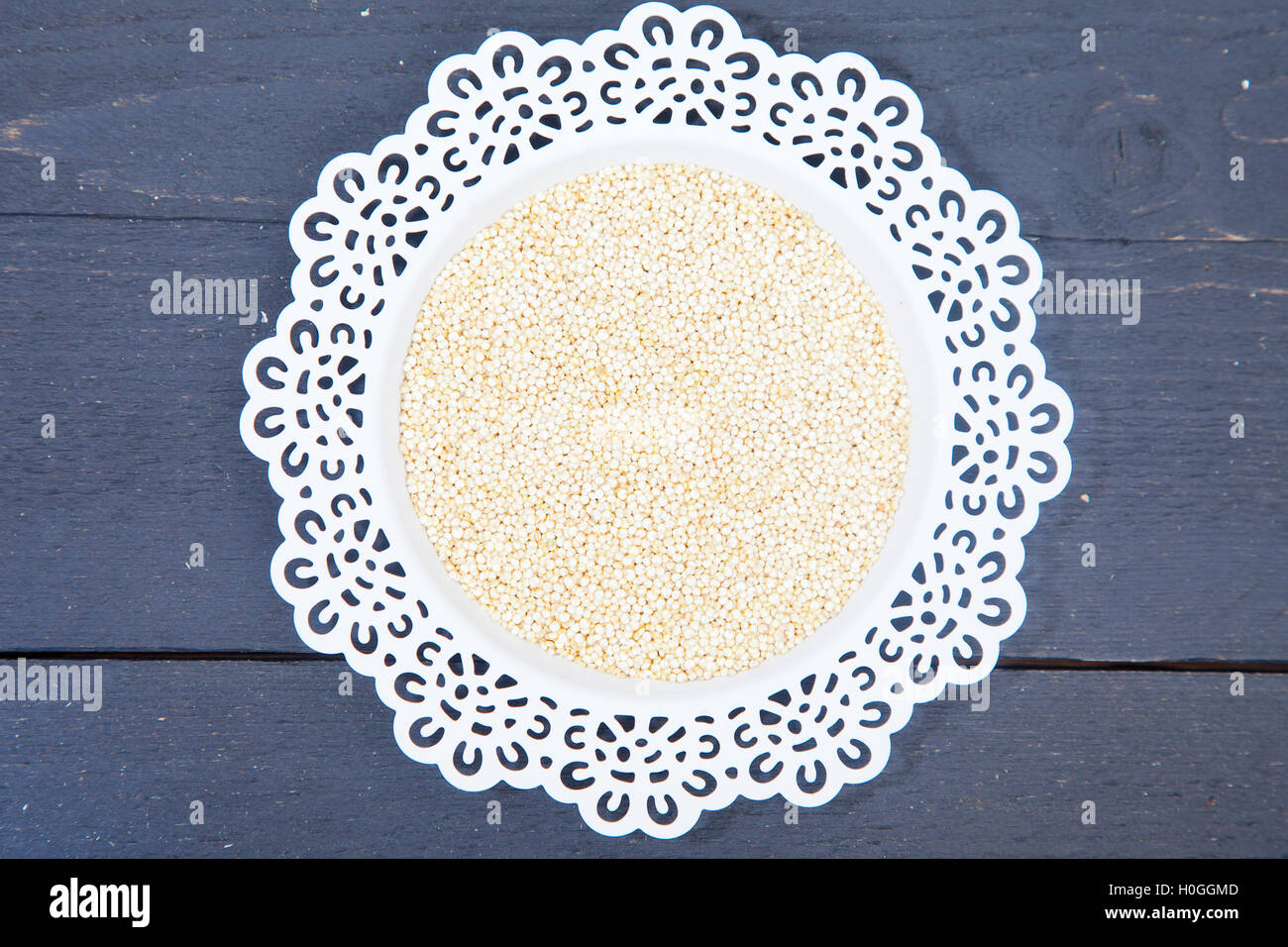 Weiße Quinoa auf weißen Teller auf schwarzem Hintergrund aus Holz Stockfoto