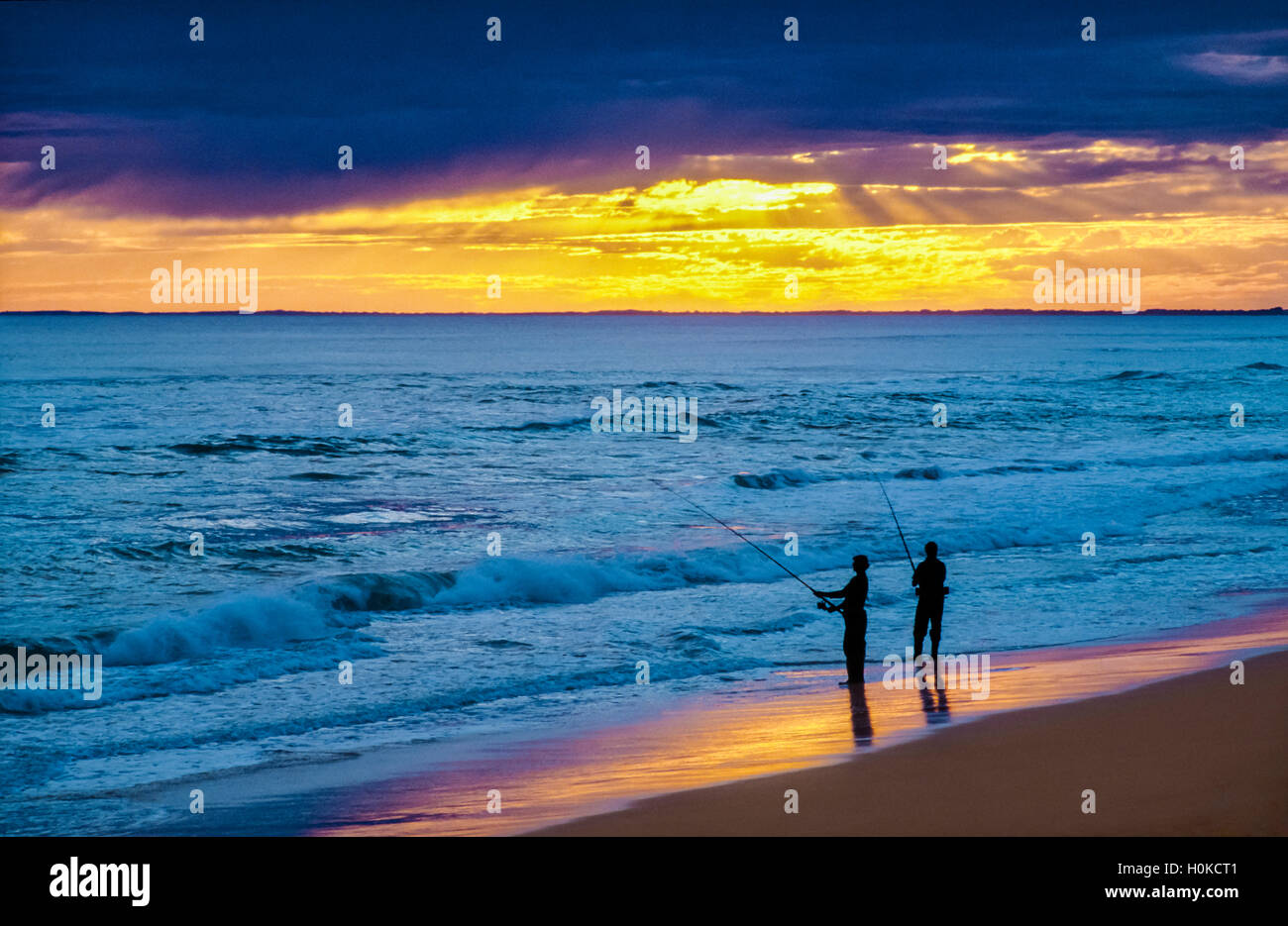 Zwei Fischer, die Silhouette gegen ankommenden Wellen und Gewitterwolken Stockfoto