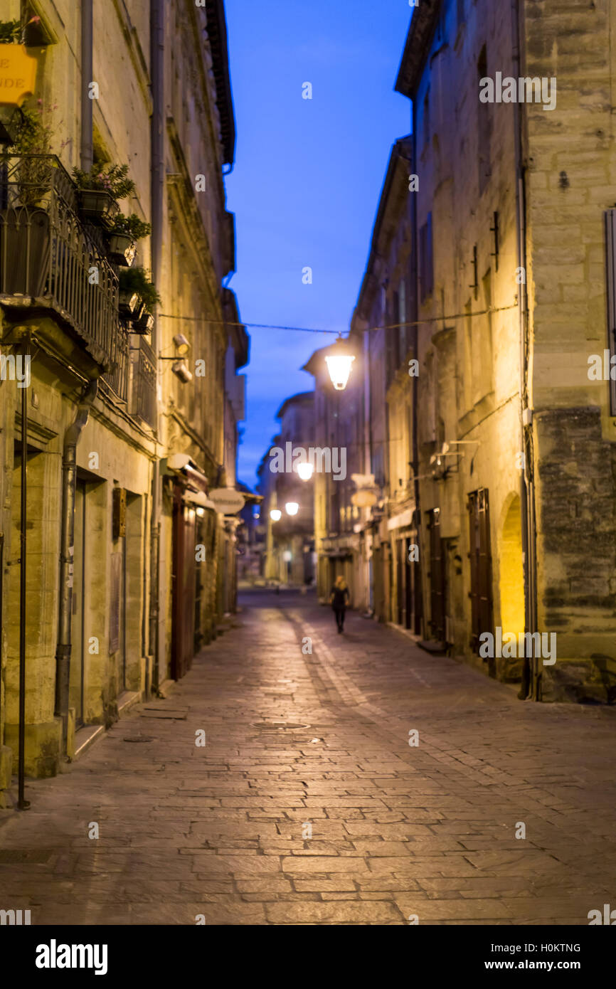 Frau zu Fuß in beleuchteten alten Straße in der Nacht, Uzes, Languedoc, Frankreich Stockfoto