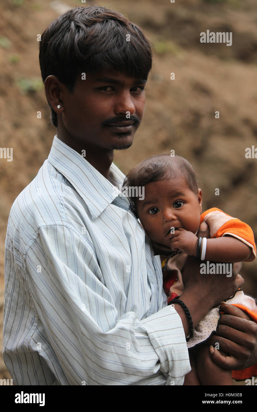 Ein Porträt eines armen indischen Arbeiters sein Baby im Arm halten Stockfoto