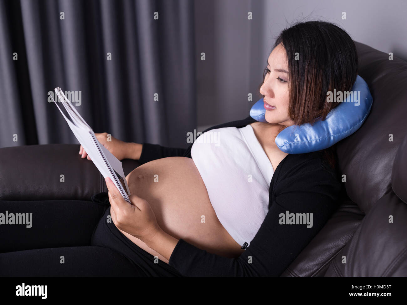 Schwangere Frau auf dem Sofa liegen und ein Buch zu lesen Stockfoto