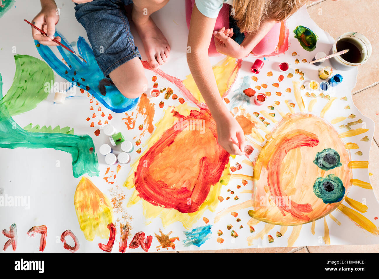Kinder malen zusammen auf einem großen Blatt Papier Stockfoto