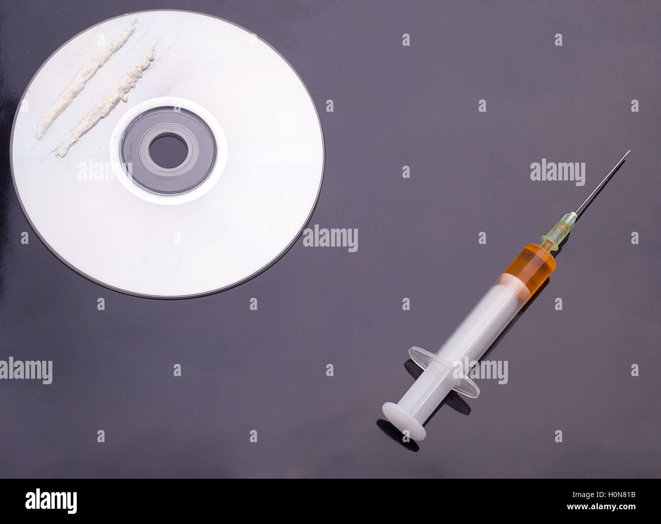 Spritze und Kokain in das DVD-Laufwerk auf einem schwarzen Hintergrund Stockfoto