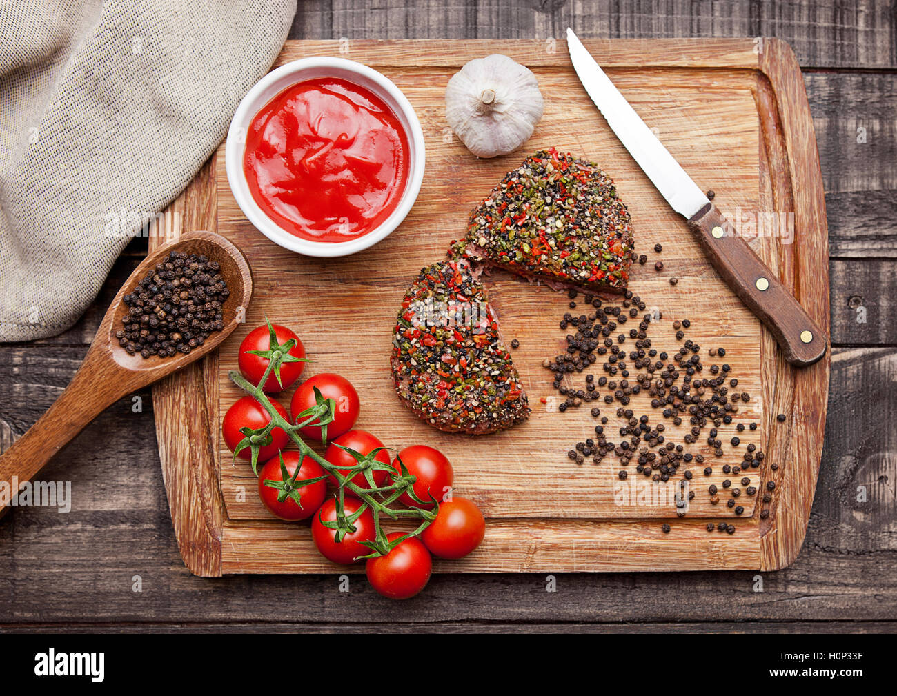 Rohes Rindersteak mit Paprika und Tomaten auf Holzbrett und hölzernen Hintergrund mit ketchup Stockfoto