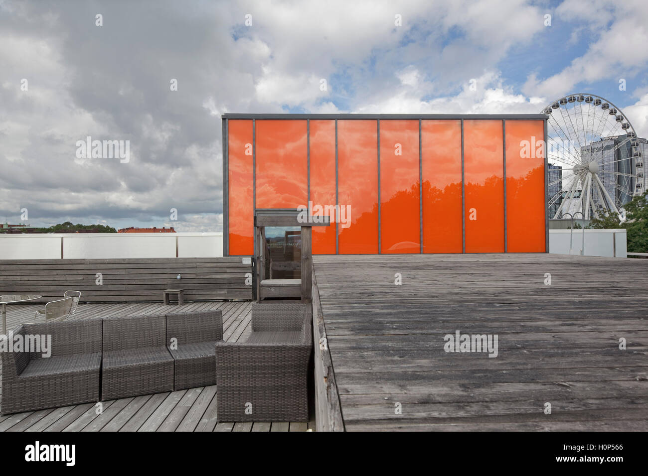 Auf dem Dach mit orange Aufzug Gehäuse und Holz decking und Vergnügungspark Liseberg im Hintergrund gegen bewölktem Himmel. Museum der Weltkultur, Göteborg, Schweden. Architekt: Brisac Gonzalez Architekten, 2004. Stockfoto