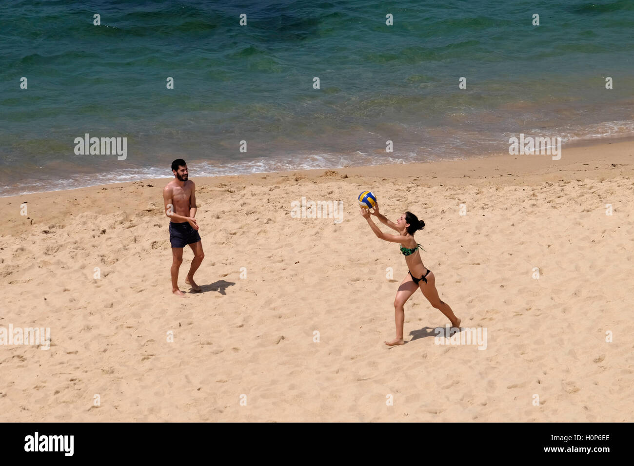 Draufsicht auf einen jungen Mann und Frau spielen Volleyball am Strand nahe dem Ozean Stockfoto