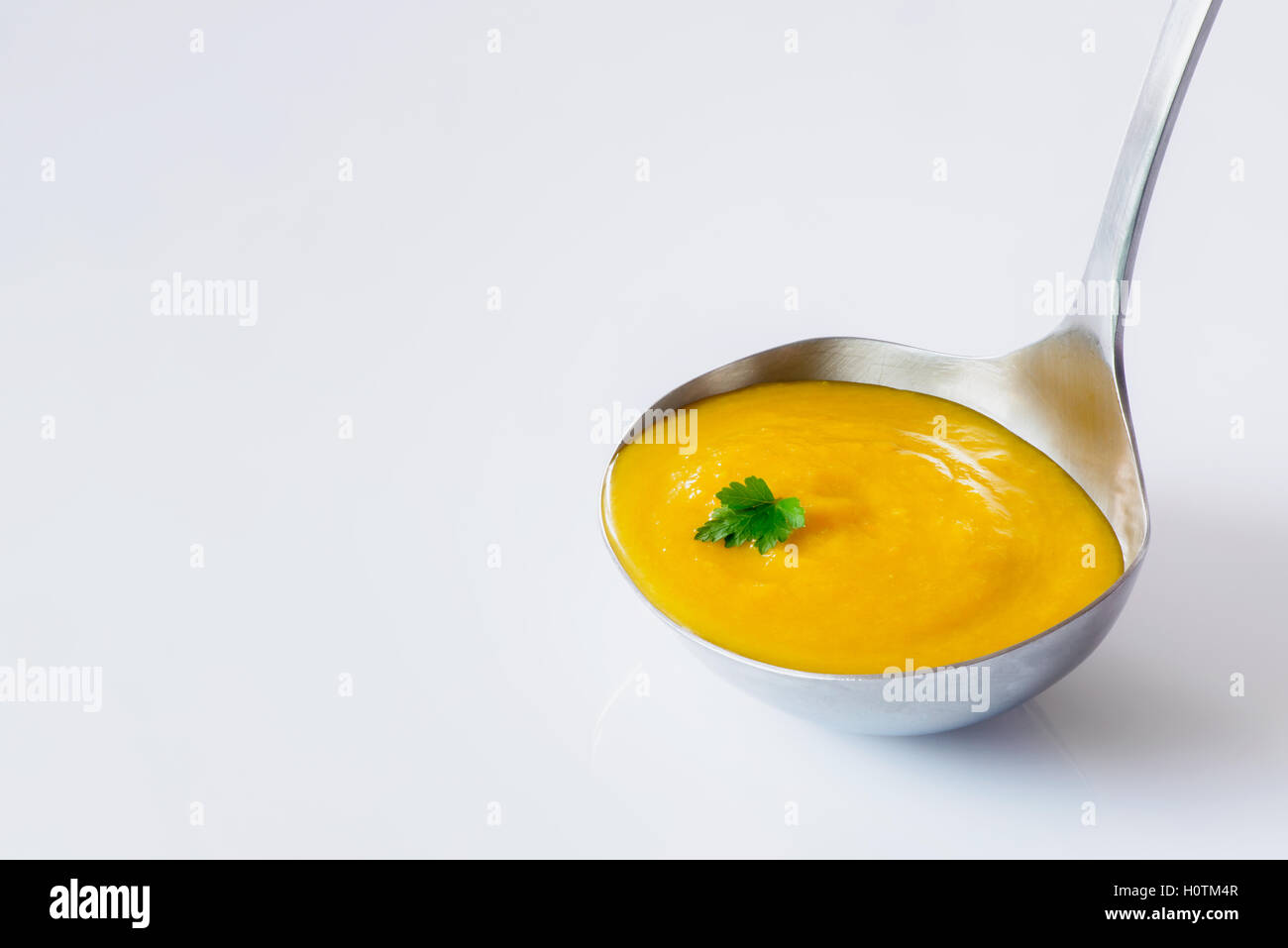 Schöpfkelle mit frischen hausgemachten Karotten Ingwer Suppe auf weißem Hintergrund Stockfoto