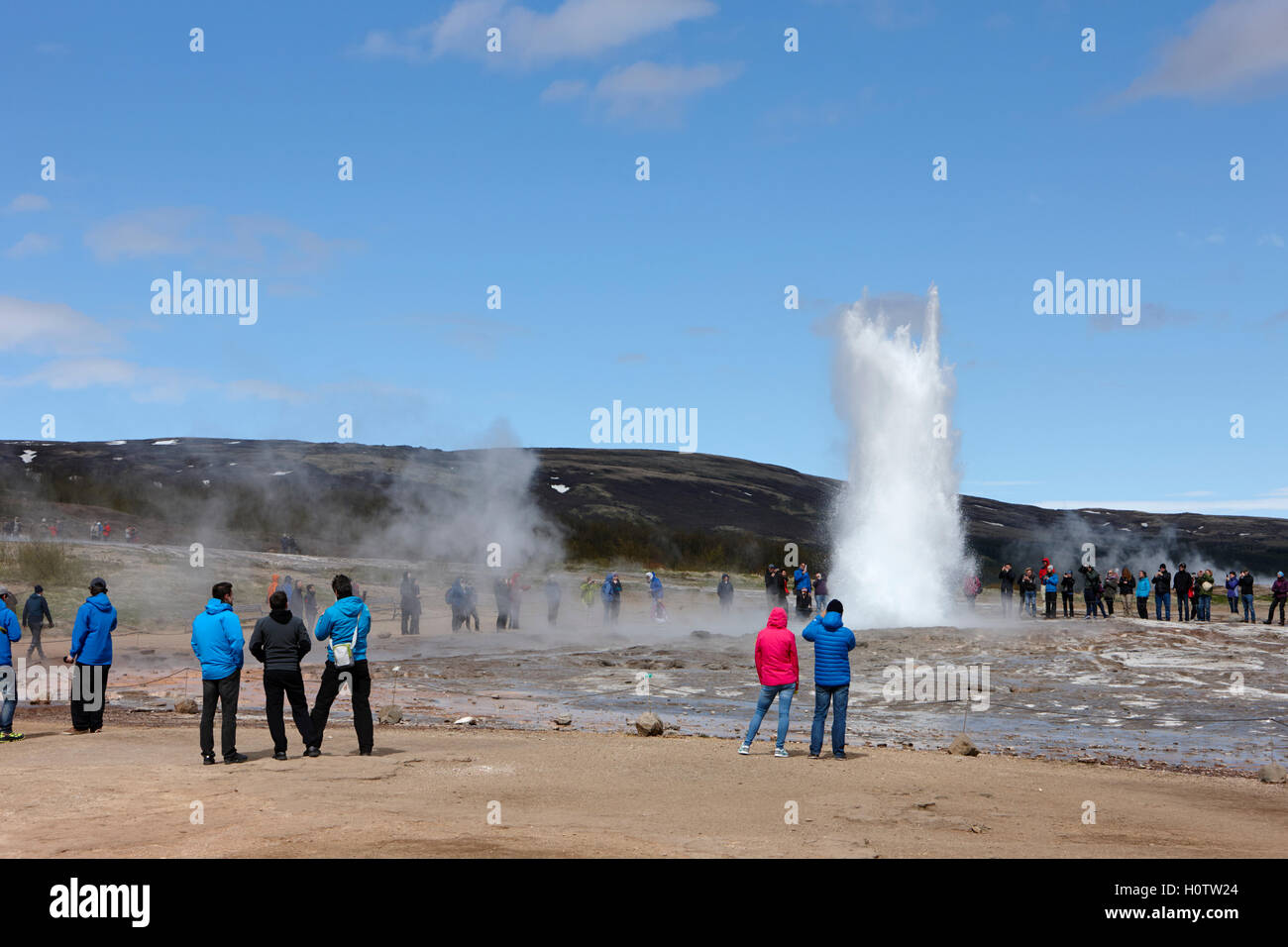 Touristen stehen herum beobachten den Strokkur-Geysir zu Geysir Island ausbrechen Stockfoto