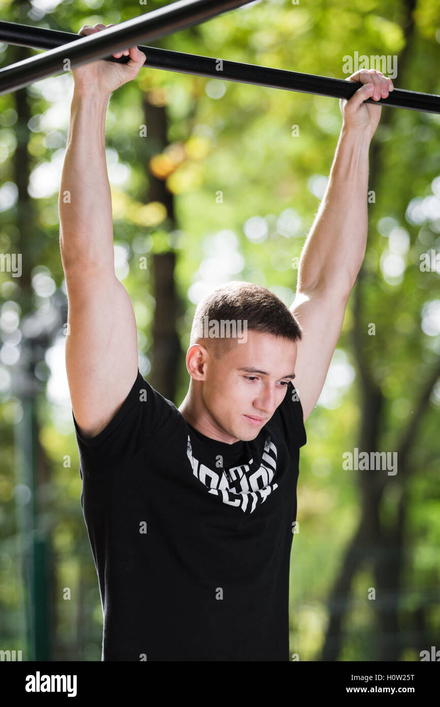 Junger Mann tun Pull Ups auf horizontale Leiste im Freien, Training, Sport-Konzept Stockfoto