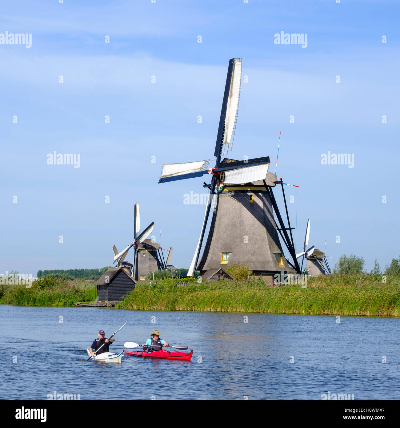 Zwei Männer in Kajaks im Kanal vor historischen Windmühlen bei Kinderdijk UNESCO-Weltkulturerbe in den Niederlanden Stockfoto