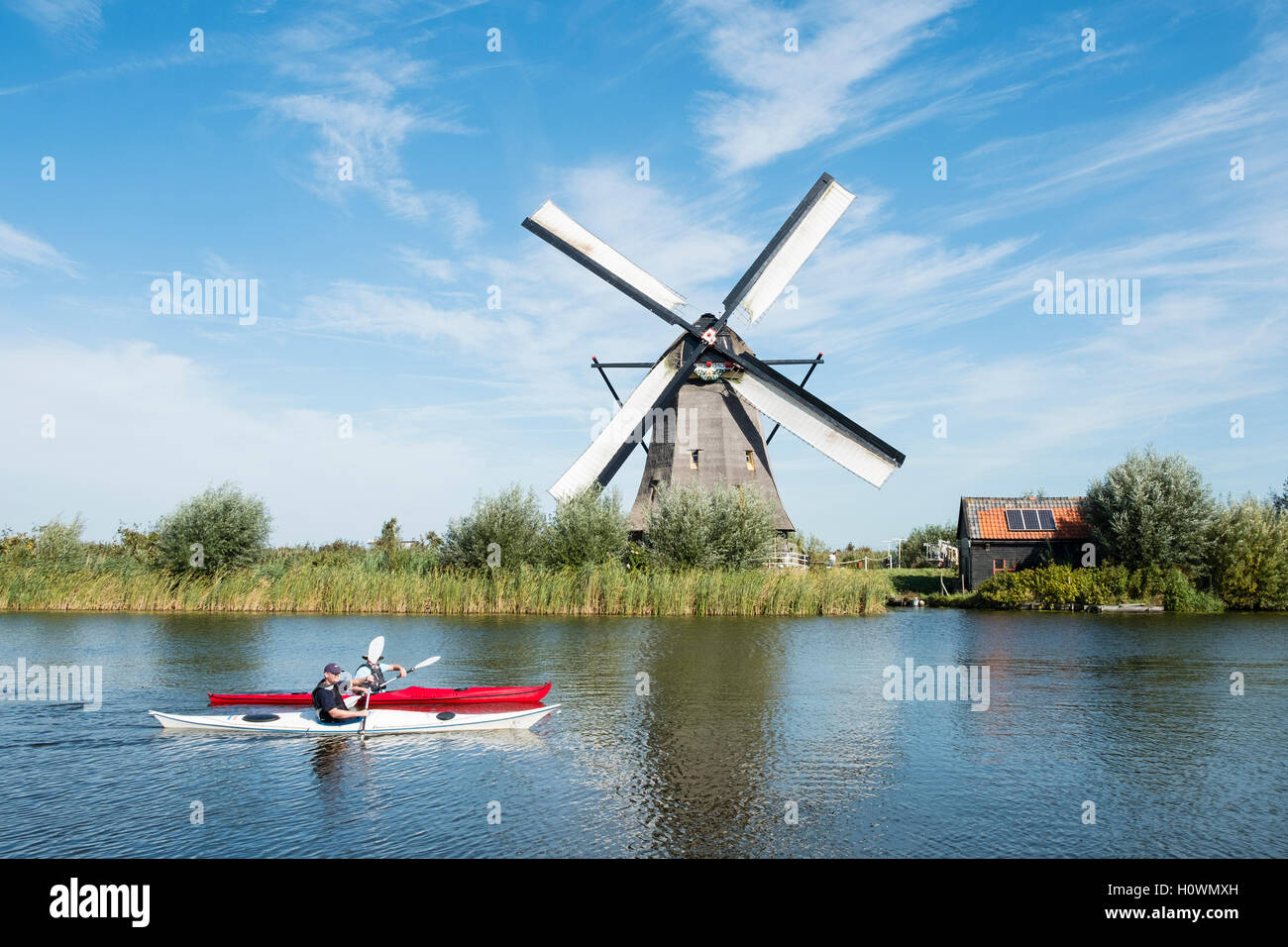 Zwei Männer in Kajaks im Kanal vor historischen Windmühlen bei Kinderdijk UNESCO-Weltkulturerbe in den Niederlanden Stockfoto