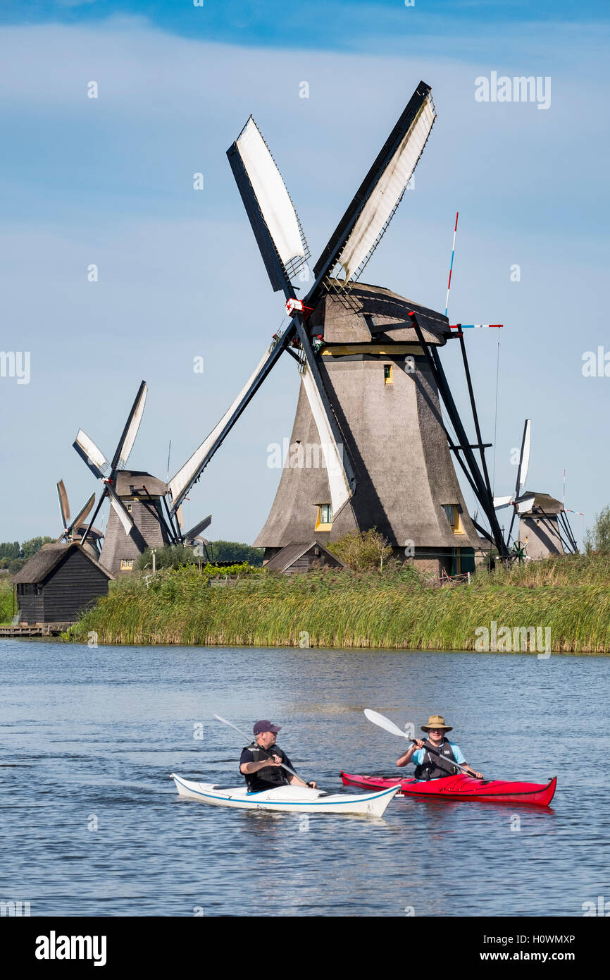 Zwei Männer in Kajaks im Kanal vor historischen Windmühlen bei Kinderdijk UNESCO-Weltkulturerbe in den Niederlanden Stockfoto