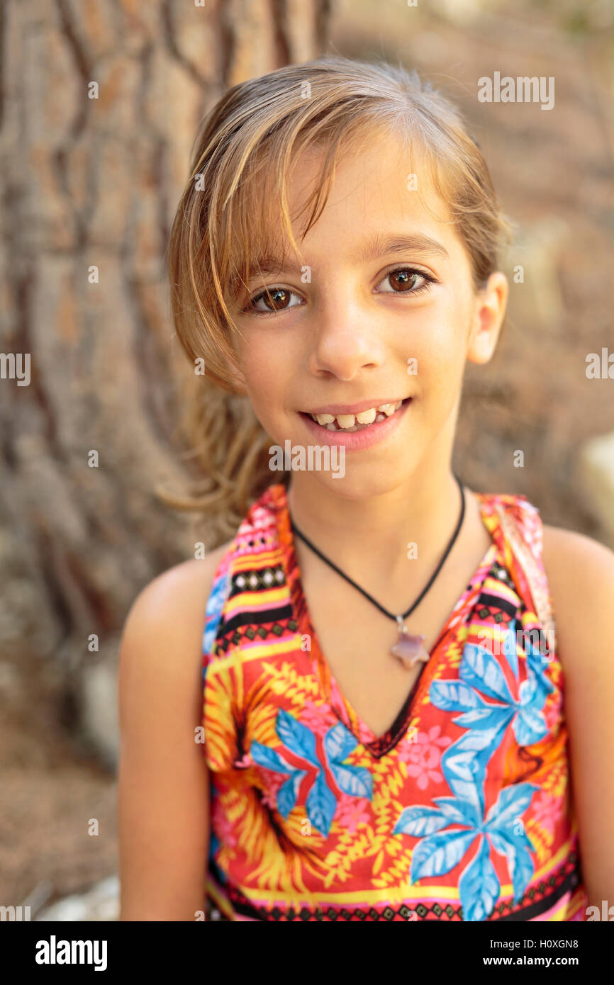 Porträt eines Mädchens neben einem Baum mit einem sehr bunten Kleid Stockfoto