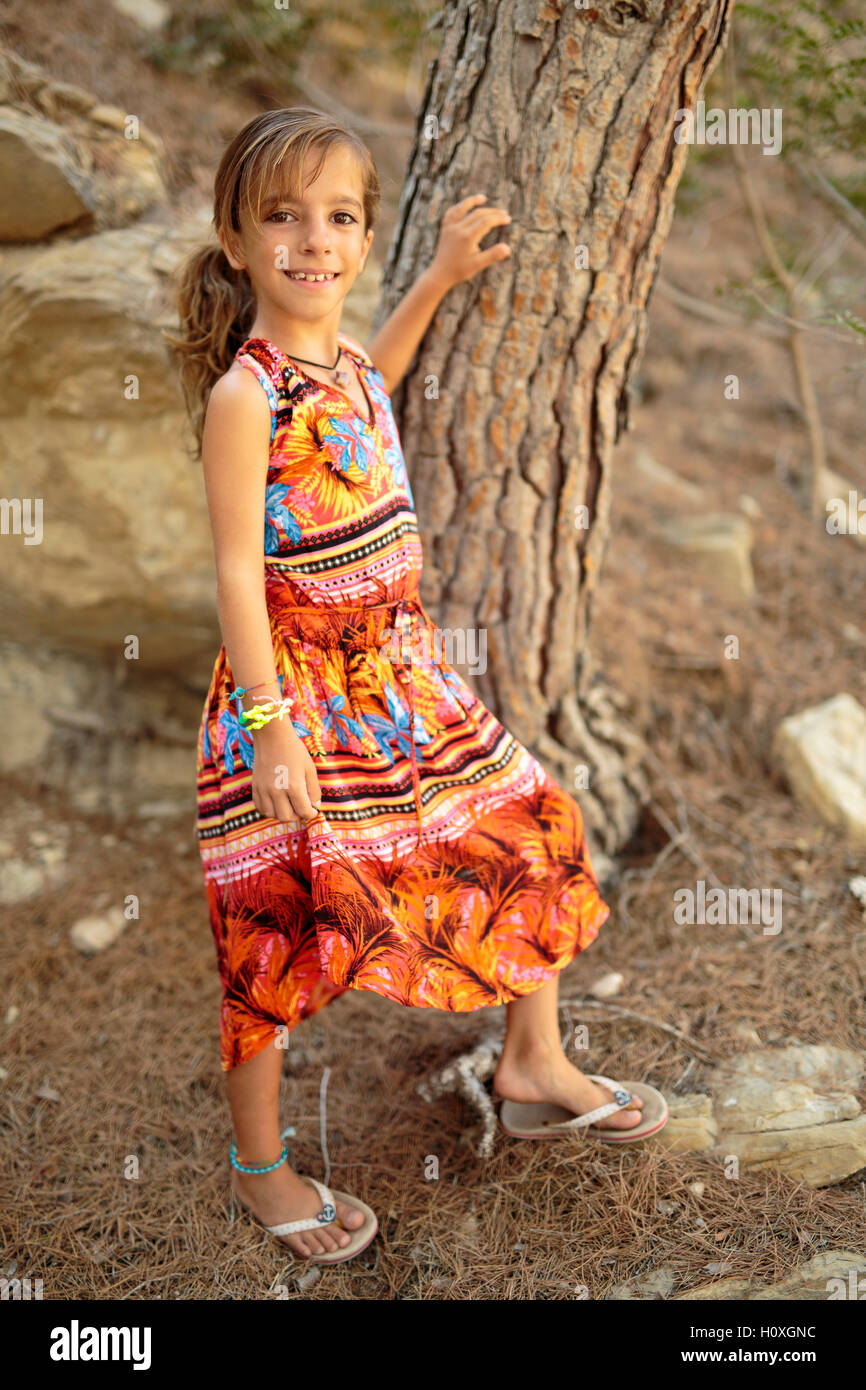 Porträt eines Mädchens neben einem Baum mit einem sehr bunten Kleid Stockfoto
