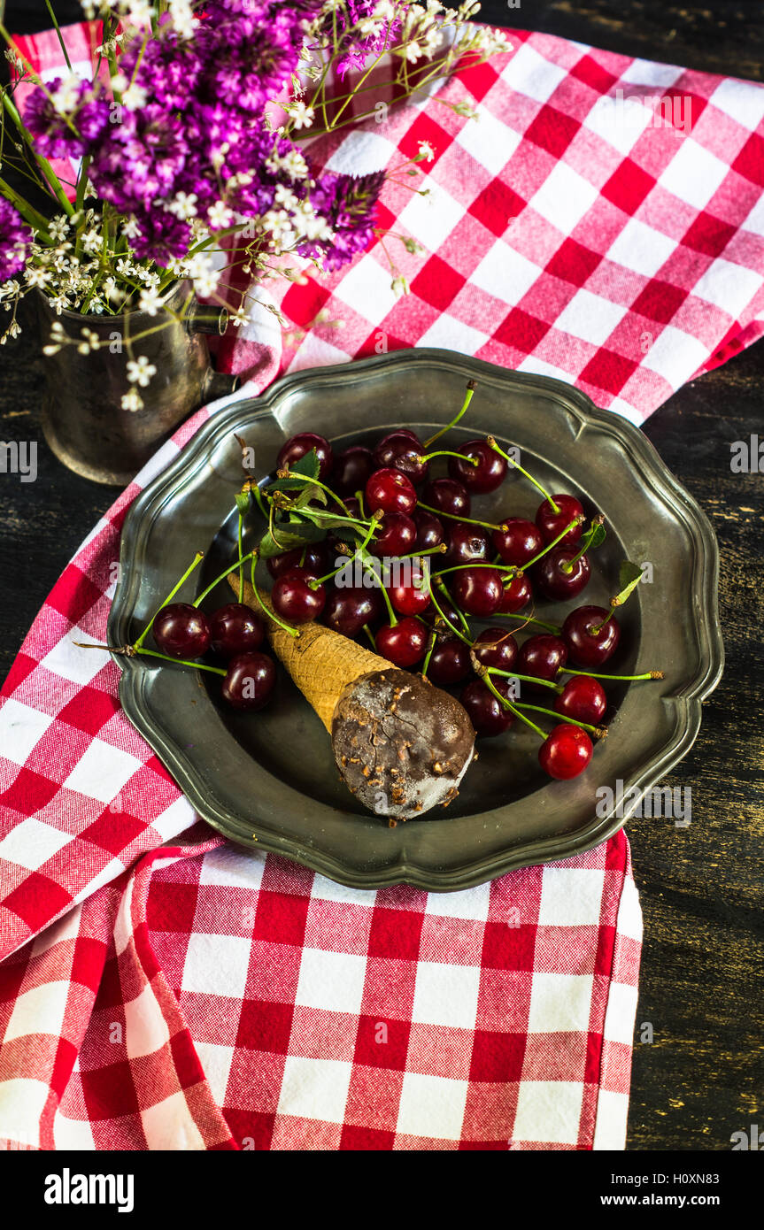 Wilde Blumen und frische Bio Kirschen mit Eis auf Vintage Teller Stockfoto
