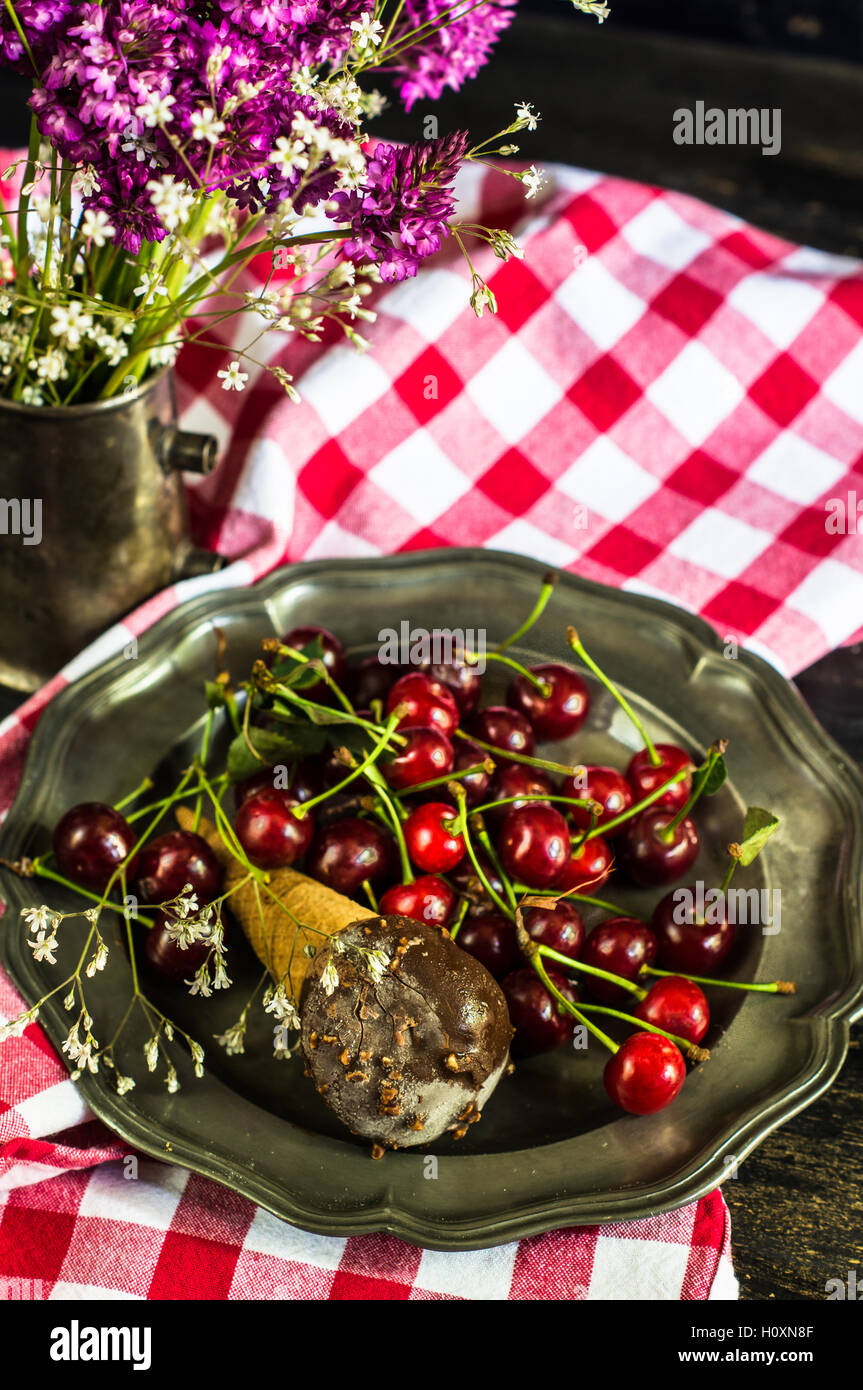 Wilde Blumen und frische Bio Kirschen mit Eis auf Vintage Teller Stockfoto