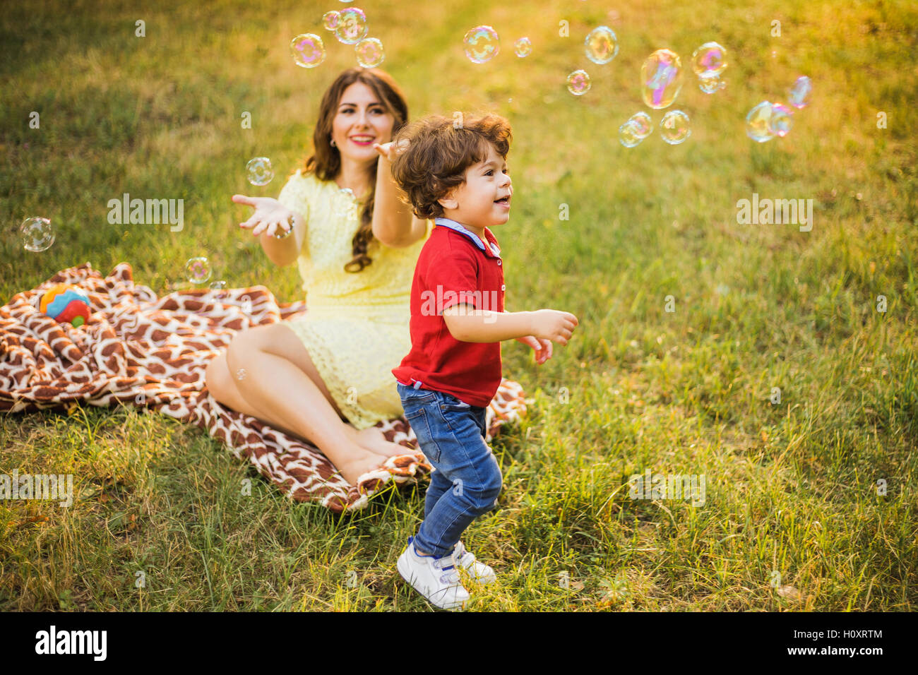 Glückliches Kind und Frau im freien Spiel mit Seifenblasen auf Wiese Stockfoto