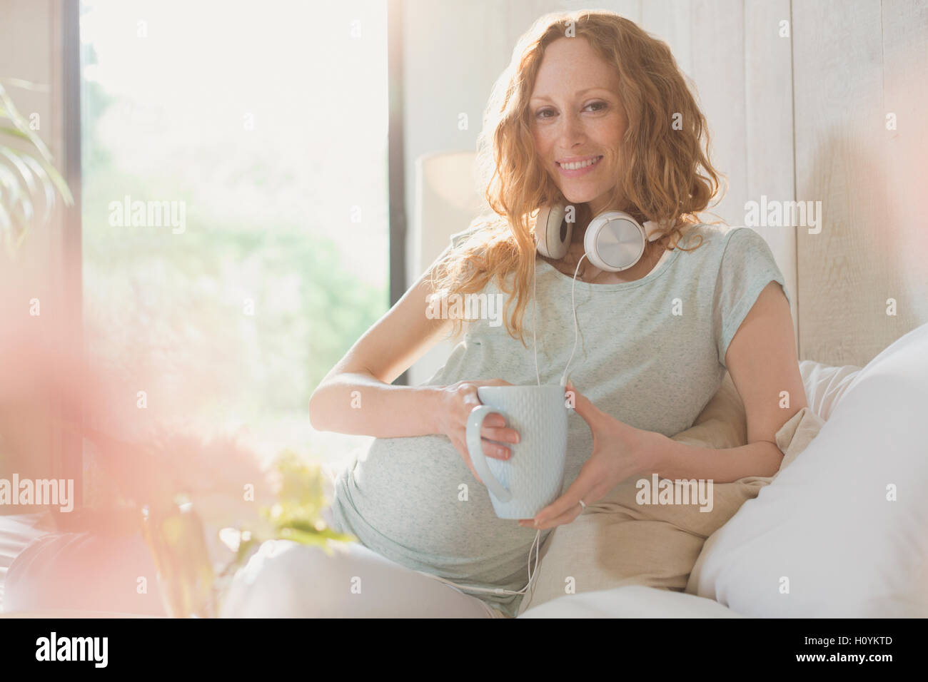 Porträt schwangere Frau Kopfhörer Tee trinken Stockfoto