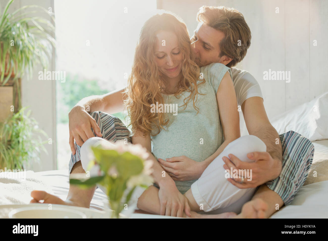 Schwangere paar küssen Pyjama ins Bett Schlafzimmer Stockfoto