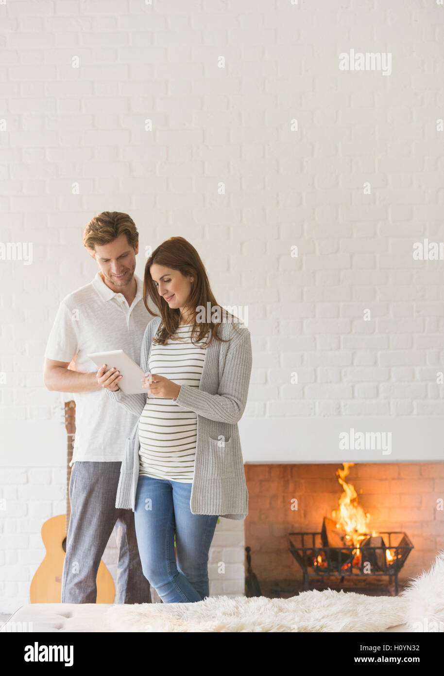 Schwangere paar mit digital-Tablette Kamin Stockfoto