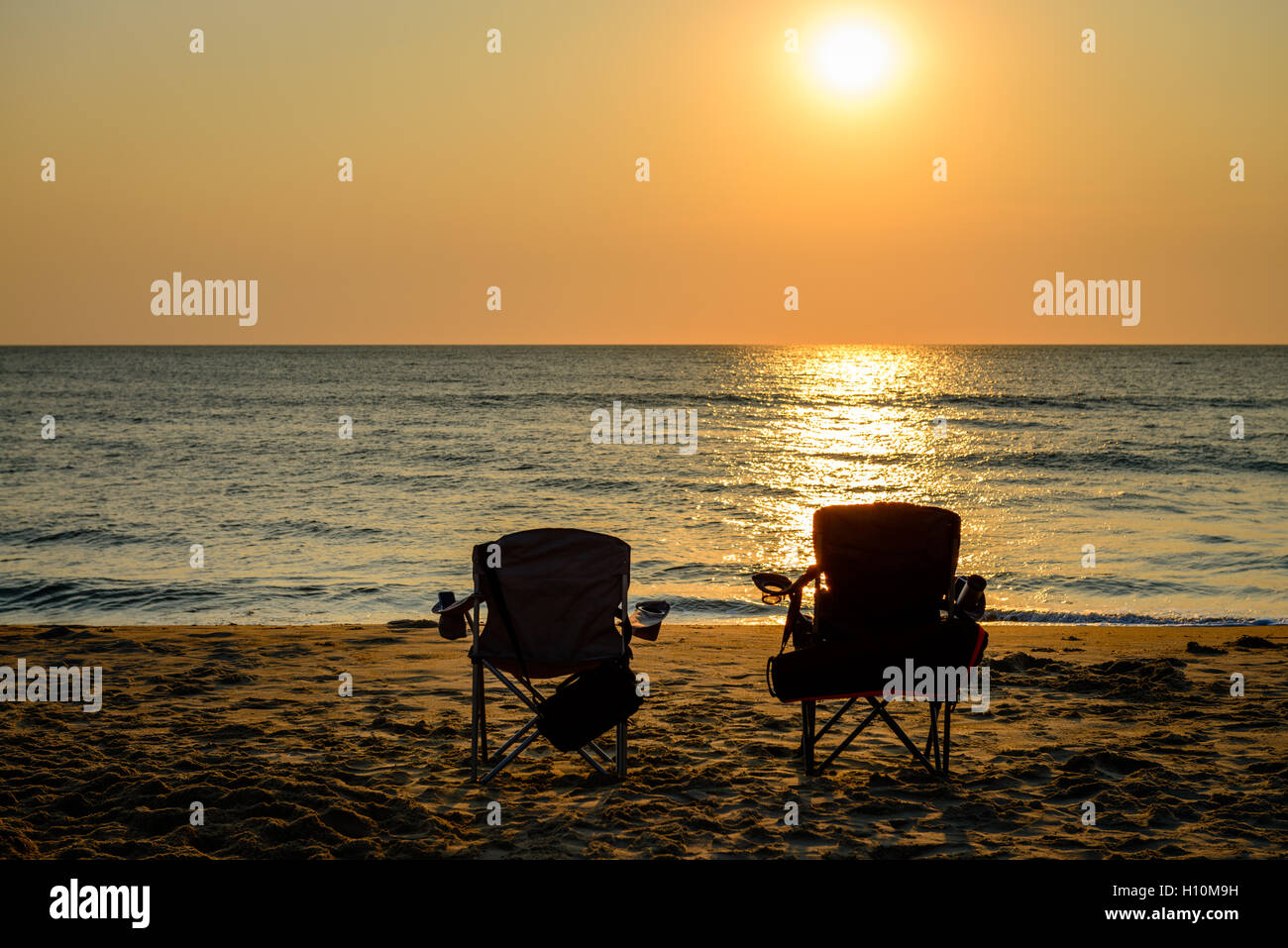 Ein schönes Bild von einem Sonnenaufgang am Strand mit zwei Klappstühle. Gefangen in Virginia Beach. Stockfoto