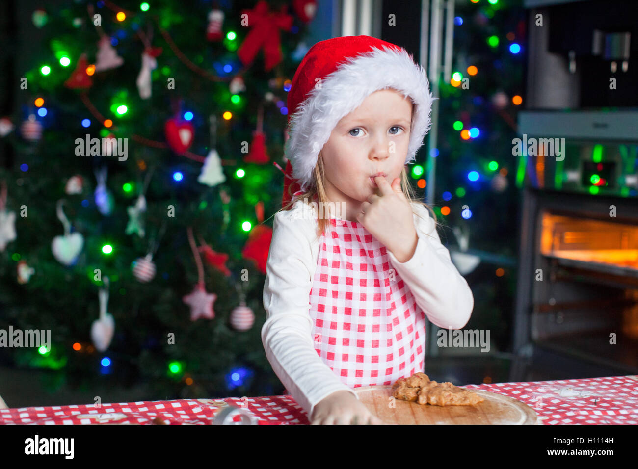 Entzückende kleine Mädchen in Essen den Teig für Ingwer Cookies Weihnachtsmütze Stockfoto