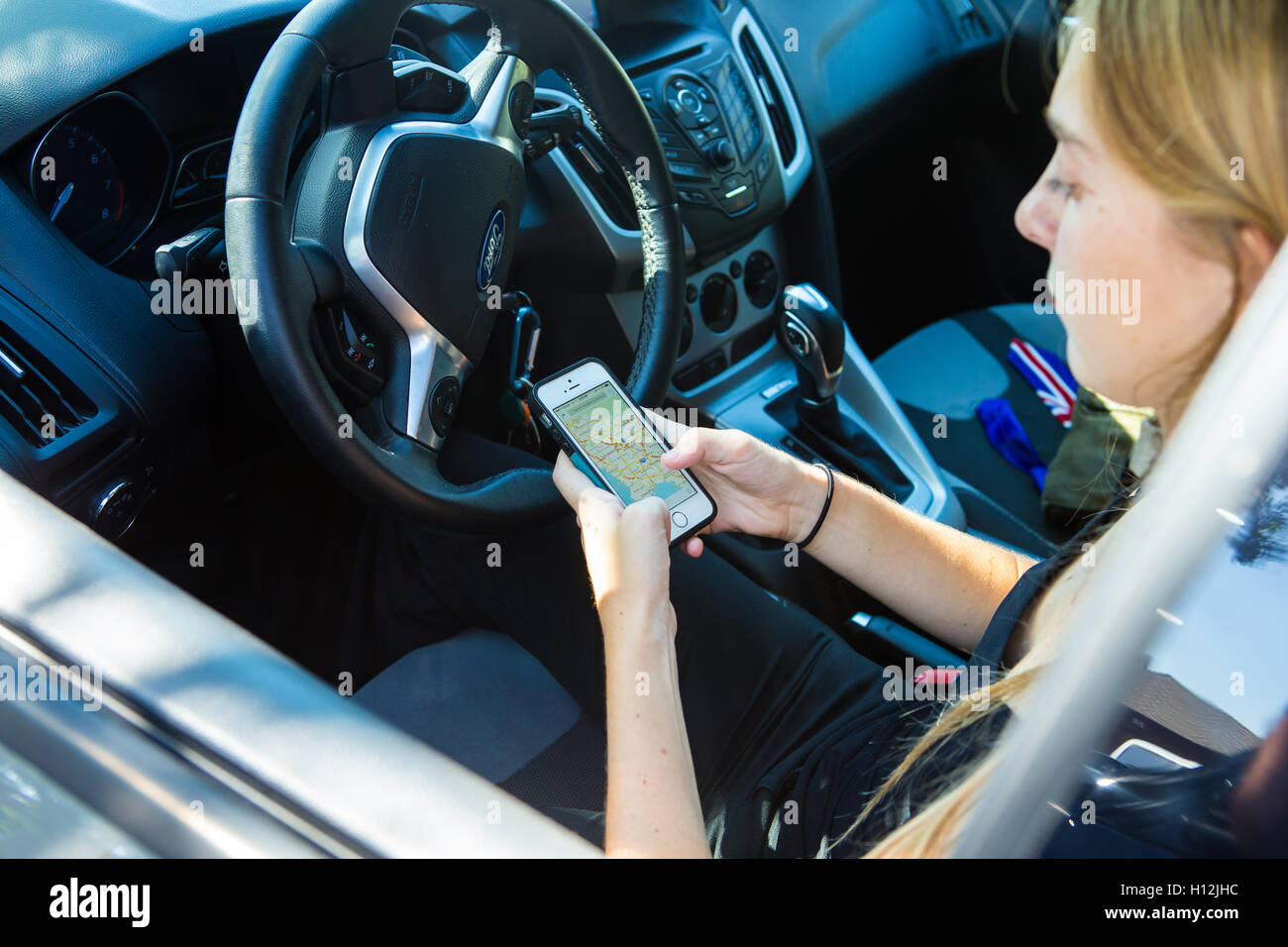 Junge Frau in ihrem Auto mit ihr i Phone 5 s, Wegbeschreibungen zu überprüfen Stockfoto