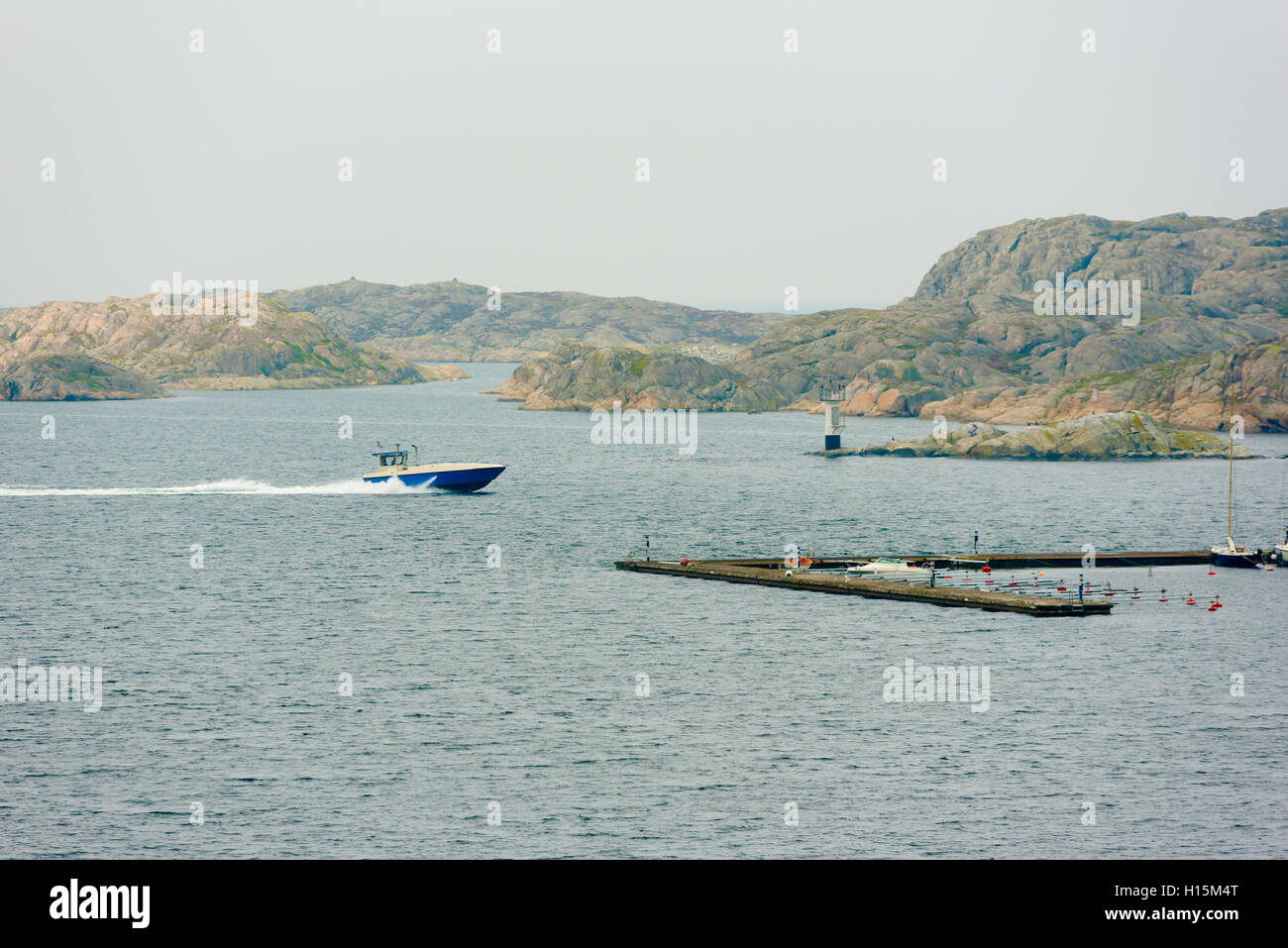 Blaue Motorboot bis zur Marina mit felsigen Inselchen im Hintergrund ein nebliger Morgen im Herbst zu beschleunigen. Der schwedischen Westküste in der Nähe von Ska Stockfoto