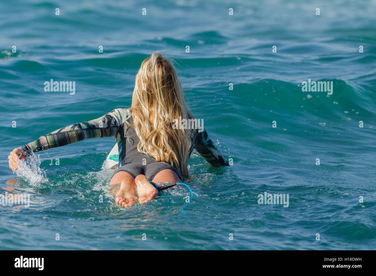 Surfer Mädchen Surfen paddeln aus Wasser des Ozeans. Stockfoto