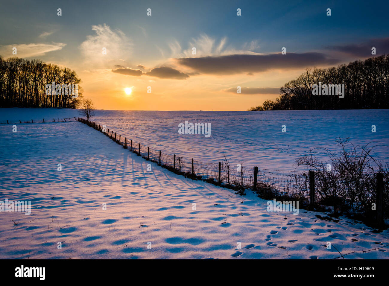 Winter-Sonnenuntergang über einen Zaun und Schnee überdachten Hof-Feld im ländlichen Carroll County, Maryland. Stockfoto
