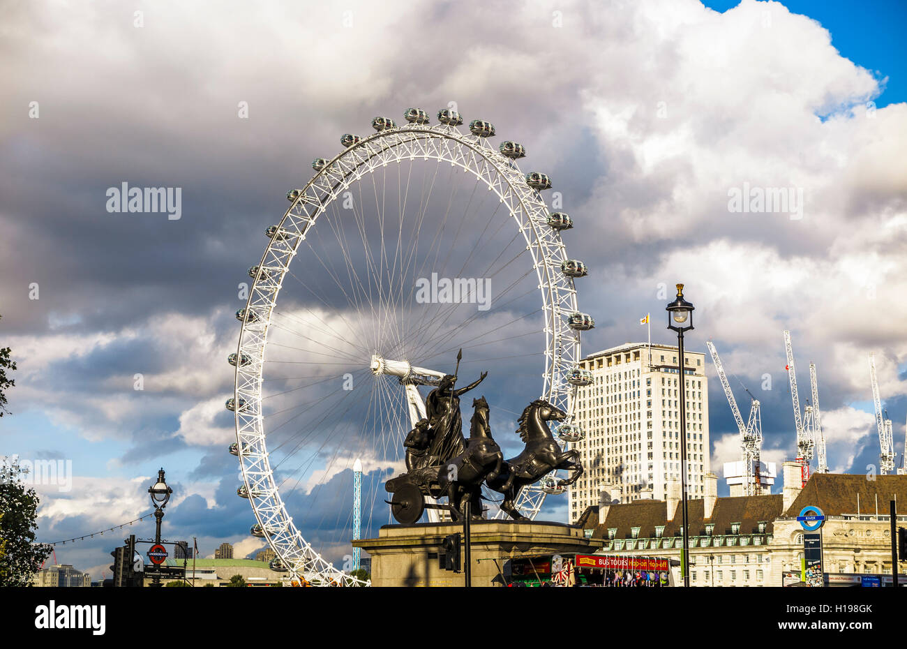 Statue von Bouddica und ihre Töchter auf der Böschung in Westminster, London, UK mit dem London Eye an einem sonnigen Tag Stockfoto