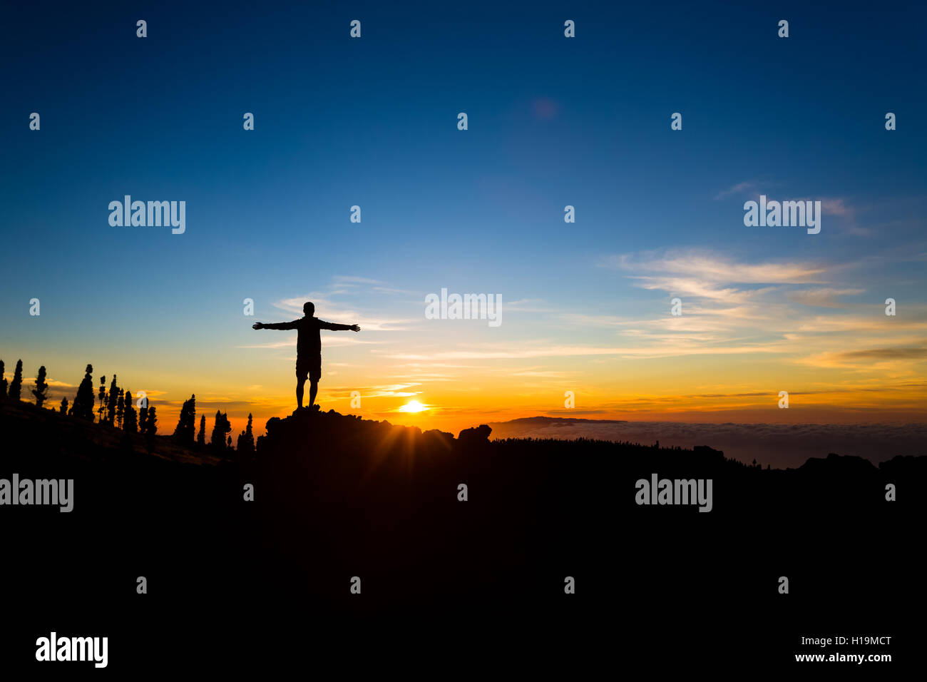 Mann mit Arme ausgestreckt feiert inspirierende Sonnenuntergang in Bergen. Männliche Wanderer oder Bergsteiger mit Händen oben genießen inspir Stockfoto