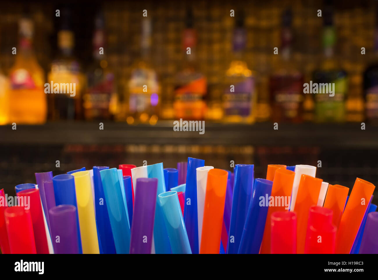 Bunte Strohhalme und unscharfen Flaschen Spirituosen und Liköre in der Bar in der Nacht Stockfoto