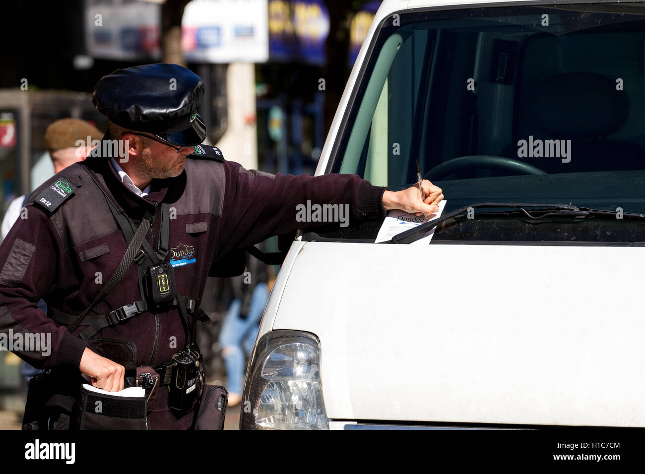 Dundee City Council Traffic Warden Ausstellung einen Strafzettel wegen eines Vergehens Parkplätze entlang der High Street in Dundee, Großbritannien Stockfoto