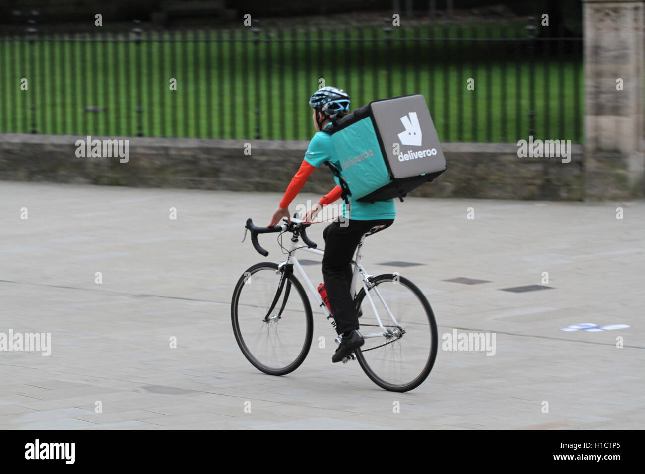 Deliveroo Radfahrer aus dem beliebter heiße Nahrung und Fast Food Lieferung Unternehmen Fahrrad durch die Straßen der Stadt. Stockfoto