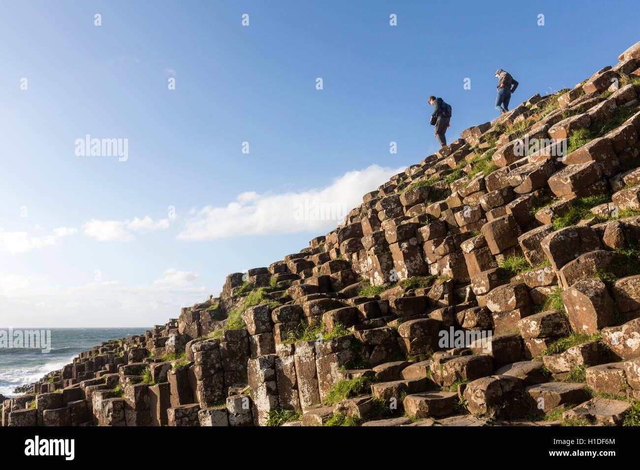 Touristen stehen auf Basaltsäulen in Giant es Causeway, Bushmills, County Antrim, Nordirland, Vereinigtes Königreich Stockfoto