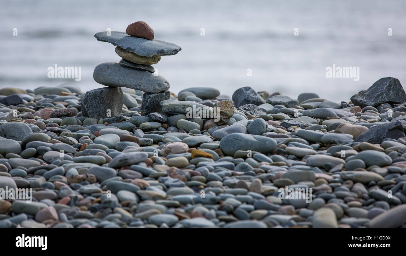 Kleinen Inukshuk an einem steinigen Strand direkt am Meer Stockfoto