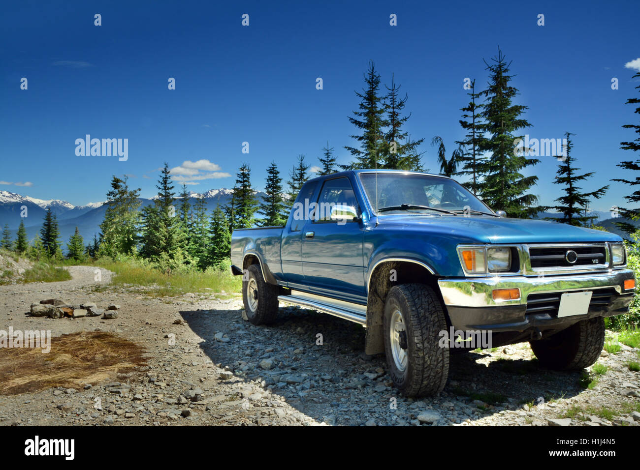 Vordere Seite des Blue Metallic LKW geparkt auf bergigen Wald Gravel Road in der Nähe von Sunny Whistler BC. HDR Art horizontale Foto Stockfoto