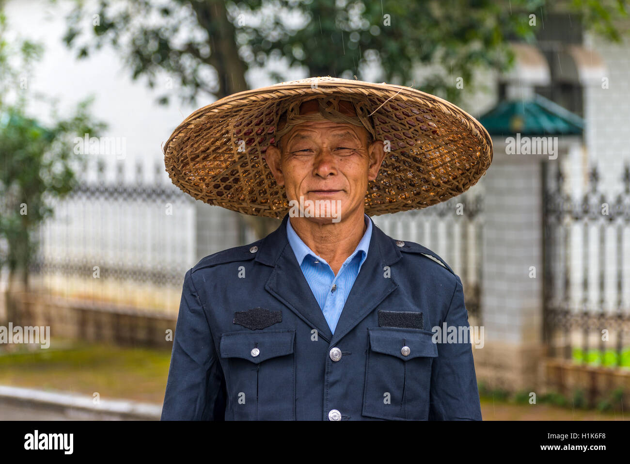 Porträt der unbekannten chinesischen Garde in traditionellen breitkrempigen Strohhut unter dem Regen Stockfoto