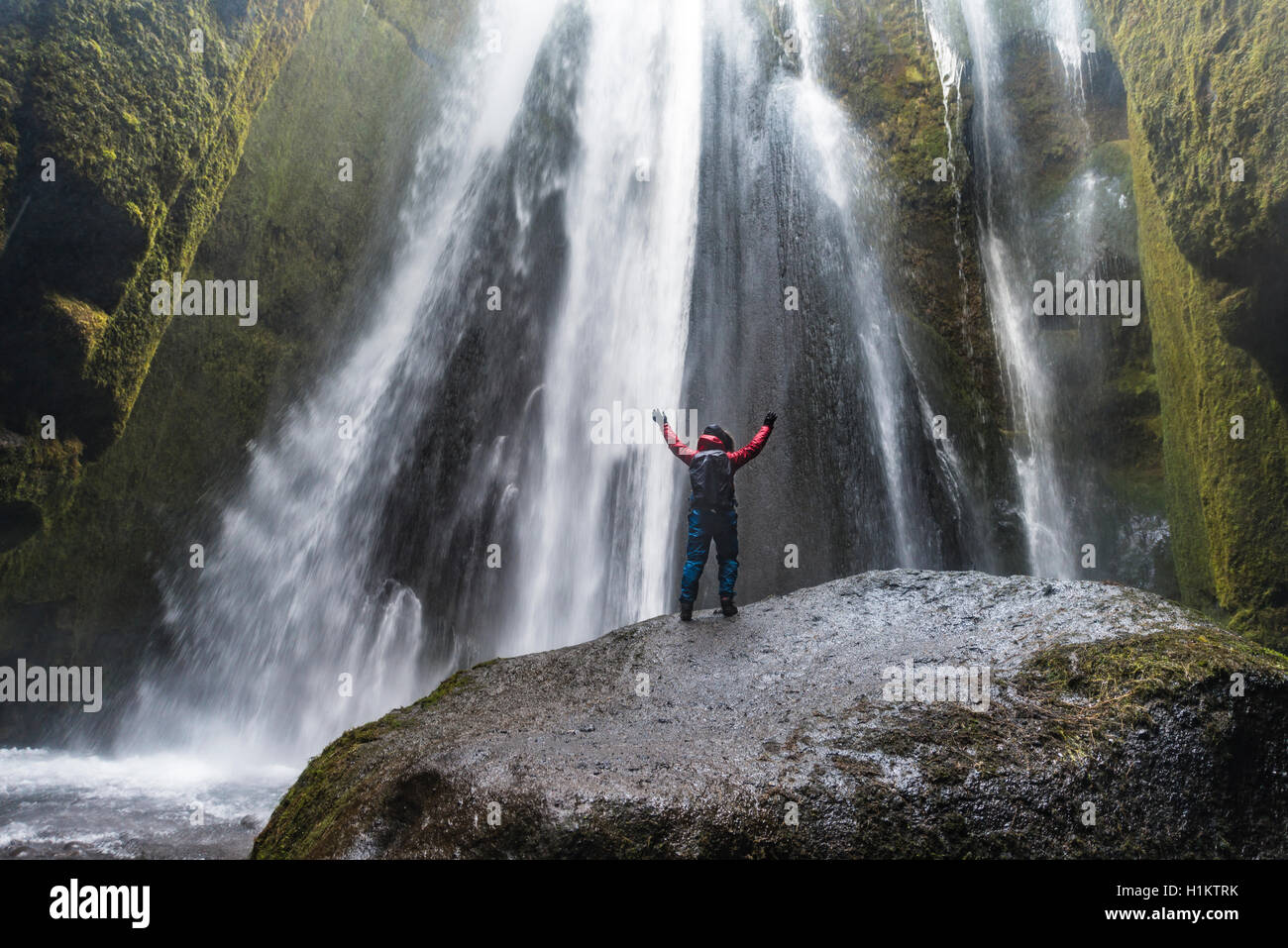 Wanderer auf Felsen vor Gljúfrabúi Wasserfall in Hamragardar, Region Süd, Island Stockfoto