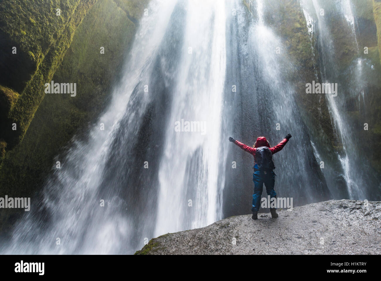Wanderer auf Felsen vor Gljúfrabúi Wasserfall in Hamragardar, Region Süd, Island Stockfoto