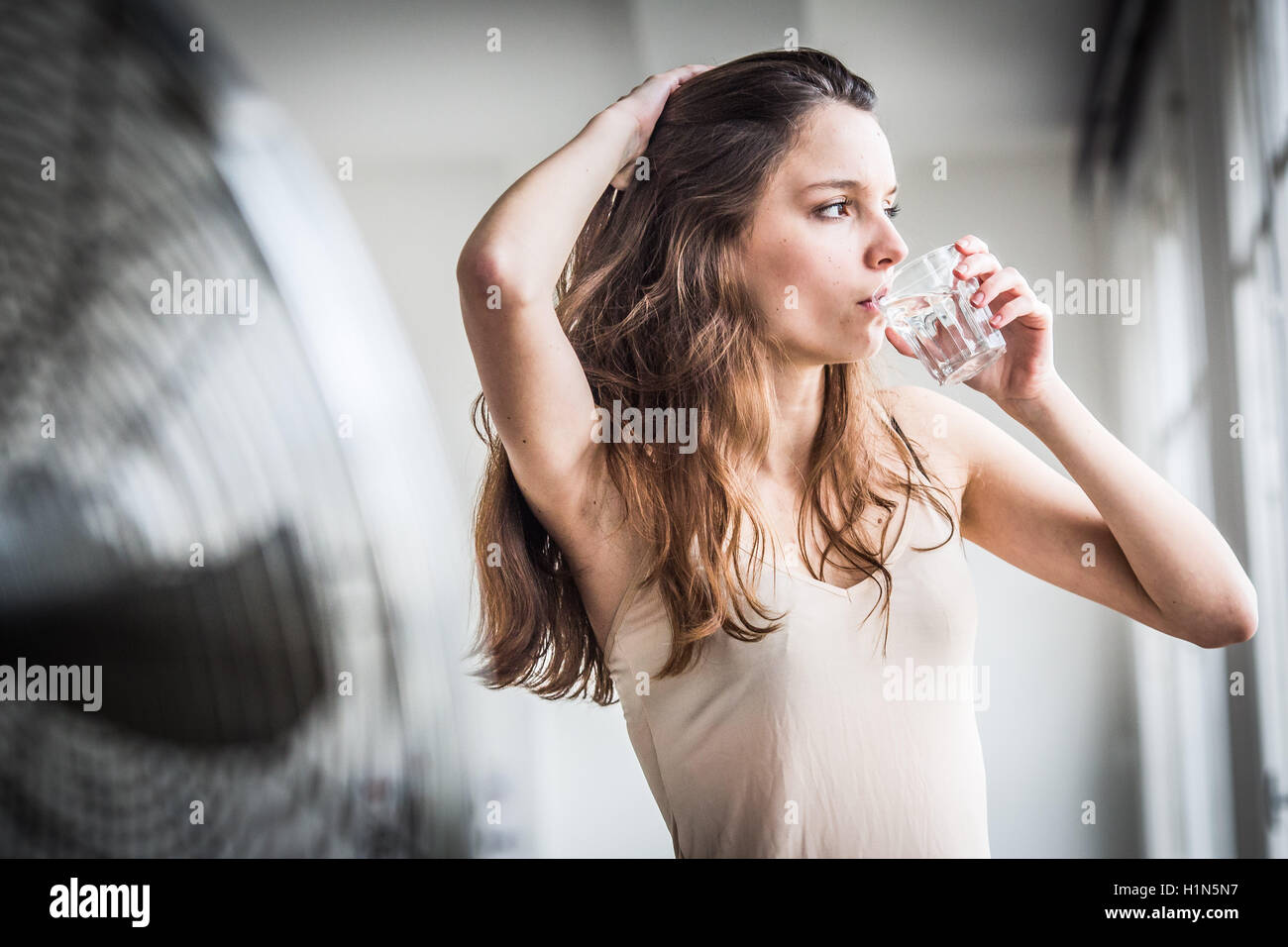 Junge Frau vor elektrischen Ventilator. Stockfoto
